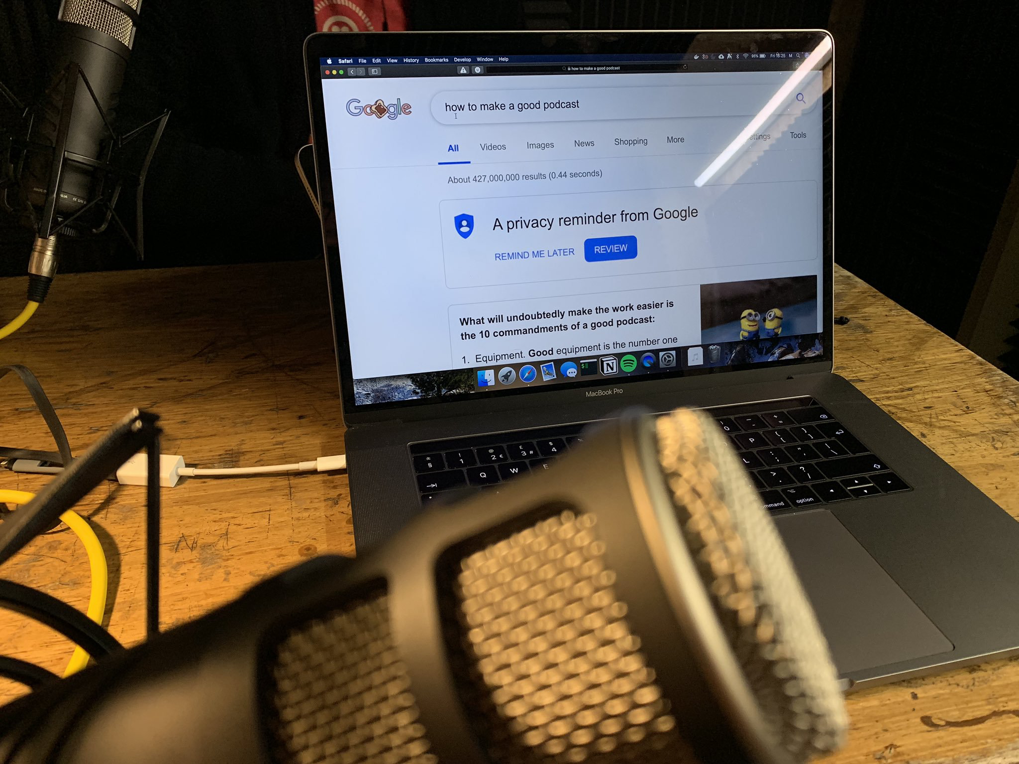 A photo of our laptop in the recording studio, and a microphone in the foreground. The laptop has a webpage up that says, "how to make a good podcast."